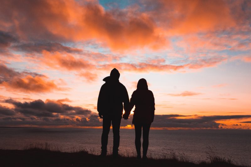 Couple holding hands looking at a sunset