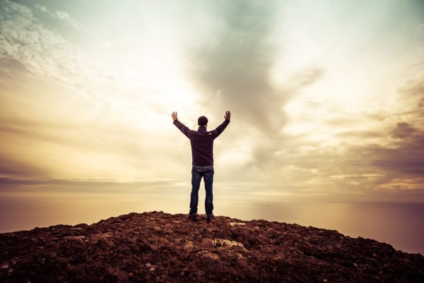 man holding his arms up towards the sky