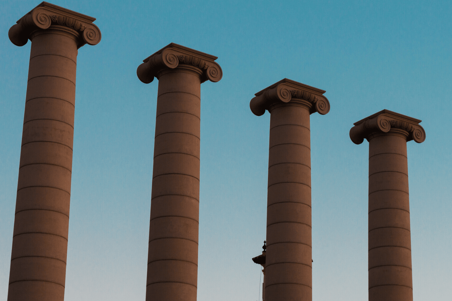 4 columns in Barcelona against a darkening blue sky