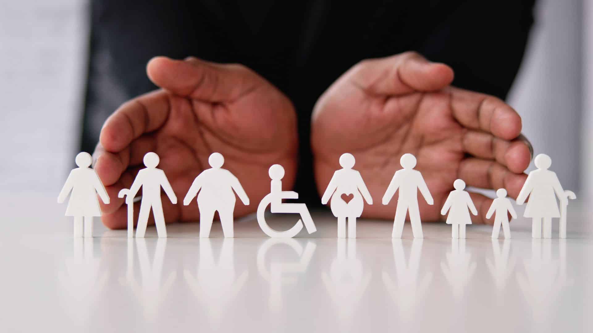 Paper cutout figures representing diverse people—including children, elderly individuals, a pregnant woman, and a person in a wheelchair—with hands positioned protectively around them.